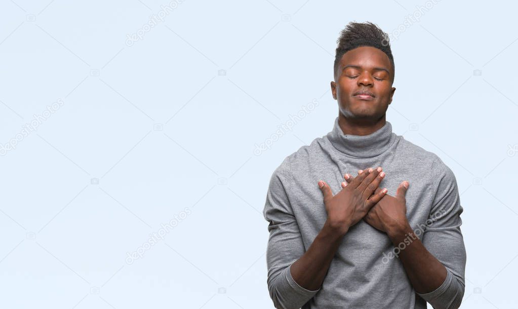 Young african american man over isolated background smiling with hands on chest with closed eyes and grateful gesture on face. Health concept.