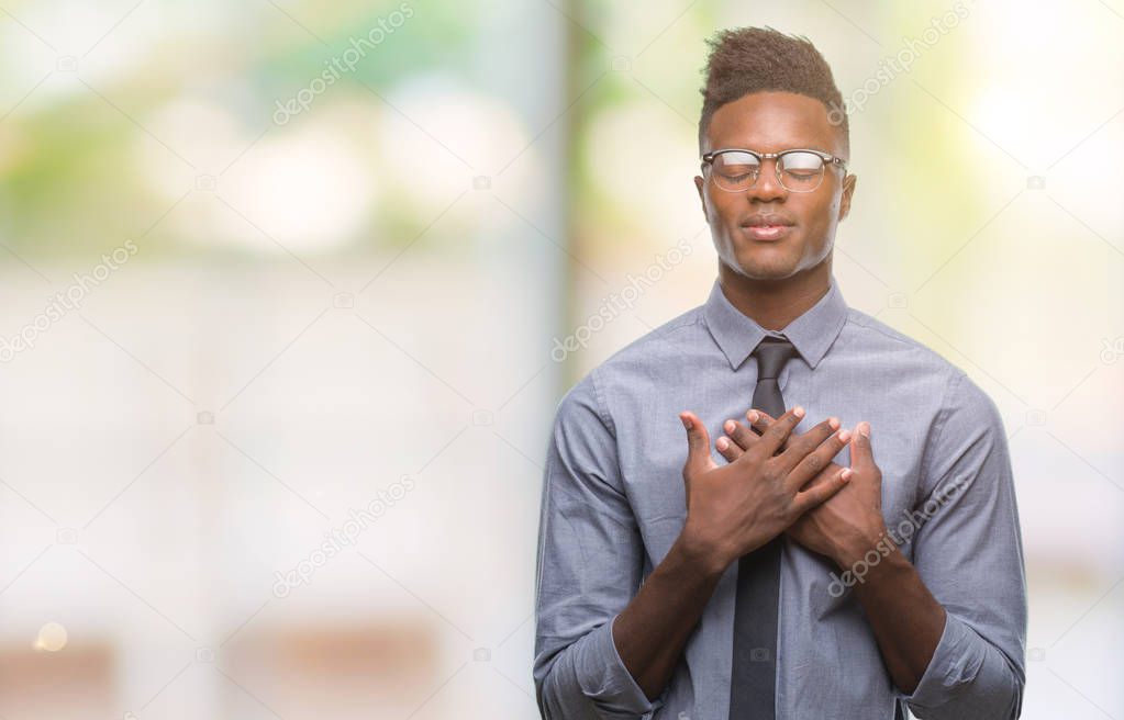 Young african american business man over isolated background smiling with hands on chest with closed eyes and grateful gesture on face. Health concept.