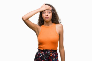 Young hispanic woman stressed with hand on head, shocked with shame and surprise face, angry and frustrated. Fear and upset for mistake. clipart