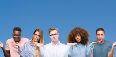 Grup mavi blackground clueless ve şaşkın bir ifadeyle kollar ve eller kaldırdı üzerine arkadaşıyla bileşimi. Şüphe kavramı.
