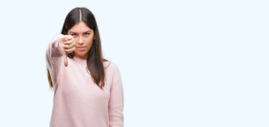 Mutsuz ve kızgın ret gösterilen ve başparmak aşağı hareketi ile negatif seyir süveter giyen genç güzel İspanyol kadın. Kötü ifade.