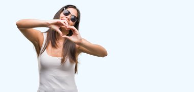İçinde gülümseyen genç güzel İspanyol giyen güneş gözlüğü kalp simgesi ve elleriyle şekil gösteren seviyorum. Romantik kavramı.
