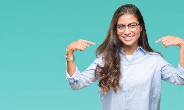 Yüzünde gülümseme ile kendinden emin görünüyorsun, kendini gururlu ve mutlu parmakları ile işaret izole arka plan üzerinde gözlük takan genç güzel Arap kadın.