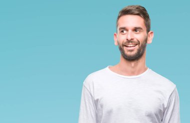 Yakışıklı delikanlı uzak tarafına yüzünde, doğal ifade gülümseme ile seyir izole arka plan üzerinde. Kendine güvenen gülüyor.