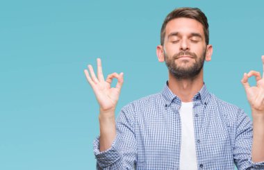 İzole arka plan üzerinde beyaz t-shirt giyen genç yakışıklı adam rahatla ve gülümseyen gözlerle kapalı parmak jestle meditasyon yapıyor. Yoga kavramı.