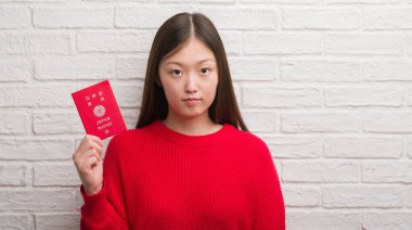Japonya pasaport acımak yüz ciddi düşünüyorum üstünde kendine güvenen bir ifade ile tutarak tuğla duvarın üzerinden Genç Çinli kadın