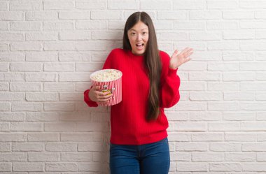 Zafer büyük gülümseme ile çığlık kutluyor ve ellerini kaldırdı pop Mısır çok mutlu ve heyecanlı, kazanan ifade yeme tuğla duvarın üzerinden Genç Çinli kadın