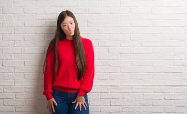 Tuğla duvar yapım balık yüzüne dudaklı, çılgın ve komik bir jest Genç Çinli kadın. Komik ifade.