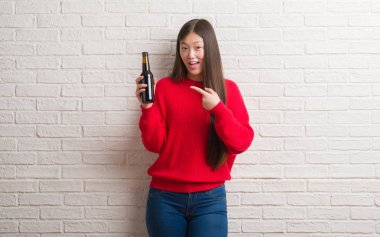 El ve parmak ile işaret çok mutlu bira içme tuğla duvarın üzerinden Genç Çinli kadın