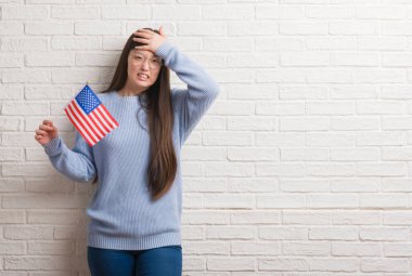 Baş, el ile vurguladı Amerika bayrağı tutarak tuğla duvarın üzerinden Genç Çinli kadın şok utanç ve sürpriz suratla, öfkeli ve sinirli. Korku ve hata için üzgün.