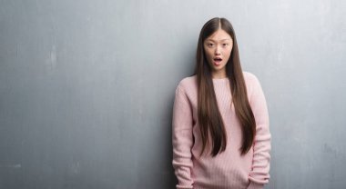 Gri duvar korkuyor ve şok sürpriz ifade, korku ve heyecan yüz Genç Çinli kadın.