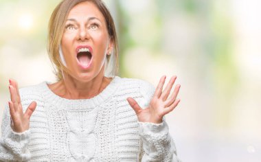 Üzerinde kış kazak giyen orta yaş üst düzey İspanyol kadın arka plan deli izole ve deli bağırarak ve agresif ifade ve silah kaldırdı bağırıyor. Hayal kırıklığı kavramı.