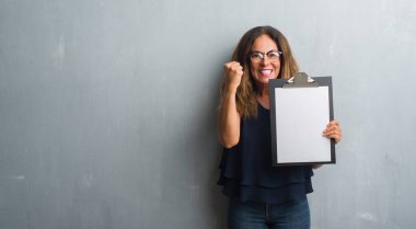 Gri grunge duvar holding Pano üzerinde duran orta yaş İspanyol kadın rahatsız ve boşa çıkarmak ile öfke, çılgın da elini, kaldırdı ile bağırıyor kavramı öfke