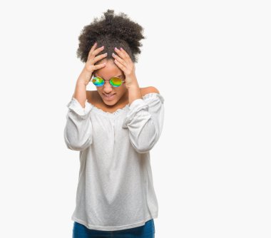 Genç afro Amerikalı kadın güneş gözlüğü takmış çünkü umutsuz ve stresli baş ağrısı acı izole arka plan üzerinde ağrı ve migren. Ellerini kafasına.