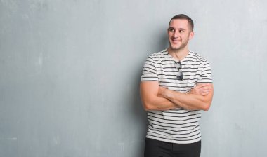 Gri grunge duvar görünümlü yan ve dik dik bakma uzağa düşünce gülümseyen Genç beyaz adam.