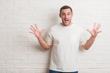 Beyaz tuğla duvar kaldırdı kollarını açarak deli ve başarı için hayran kutluyor ve açık gözleri heyecanlı çığlık üzerinde duran beyaz delikanlı. Kazanan kavramı