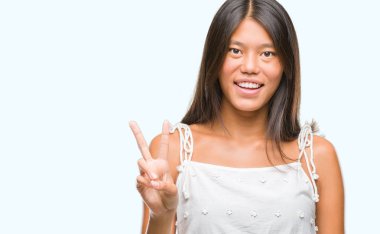 Genç Asyalı kadın mutlu yüz zafer işareti yaparken kameraya göz kırpıyor ile gülümseyen izole arka plan üzerinde. İki numaralı.