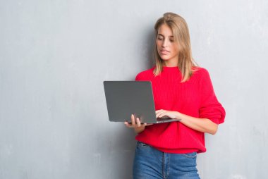 Acımak yüz ciddi düşünüyorum üstünde kendine güvenen bir ifade ile bilgisayar dizüstü kullanarak grunge gri duvar güzel genç kadın