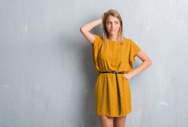 Grunge üzerinde duran güzel genç kadın elbise karıştırmayın giyen duvar gri ve soru hakkında merak ediyorum. Şüphe, kafasına el ile düşünme ile belirsiz. Dalgın kavramı.