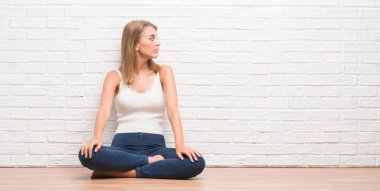 Evde katta oturan güzel genç kadın kendine güvenen gülümseme ile doğal yüz pozuyla profil rahatla tarafına, seyir.