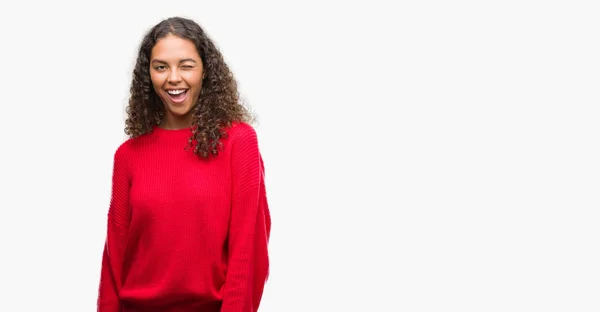セクシーな表情 明るく 幸せな顔でカメラを見てウィンクしている赤いセーターを着ている若いヒスパニック系女性 — ストック写真