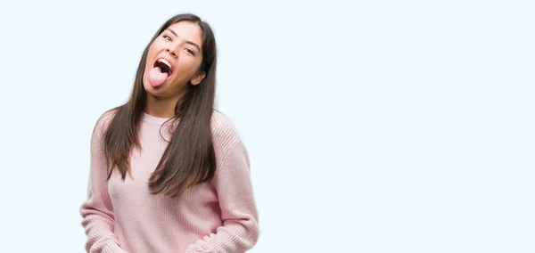 年轻漂亮的西班牙裔妇女穿着一件毛衣伸出舌头 快乐的表达高兴 情感概念 — 图库照片