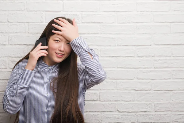 Молодая Китаянка Кирпичной Стеной Разговаривающая Телефону Напряженная Рукой Голове Шокированная — стоковое фото