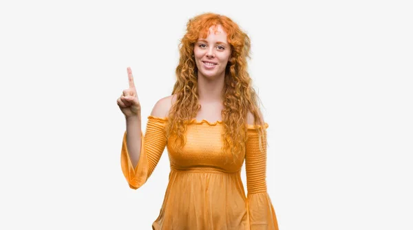 若い赤毛の女性指ナンバーワン ニコニコしながら自信を持って 幸せに上向きの表示と — ストック写真
