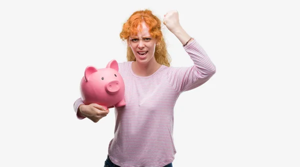 Unga Rödhårig Kvinna Anläggning Piggy Bank Irriterad Och Frustrerad Skrika — Stockfoto