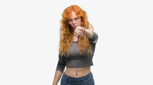 年轻的红头发的女人看着不开心和愤怒显示拒绝和否定与拇指向下手势 错误的表达式 — 图库照片