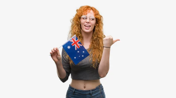 若い赤毛の女性をオーストラリアの国旗を保持して指していると幸せそうな顔を笑顔で側まで親指で示す — ストック写真
