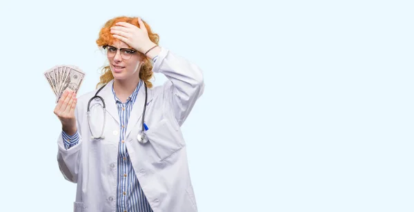 Young Redhead Doctor Woman Holding Dollars Stressed Hand Head Shocked — Stock Photo, Image