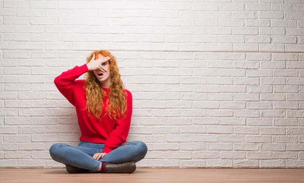 Mujer Pelirroja Joven Sentada Sobre Pared Ladrillo Asomándose Cara Cubierta —  Fotos de Stock