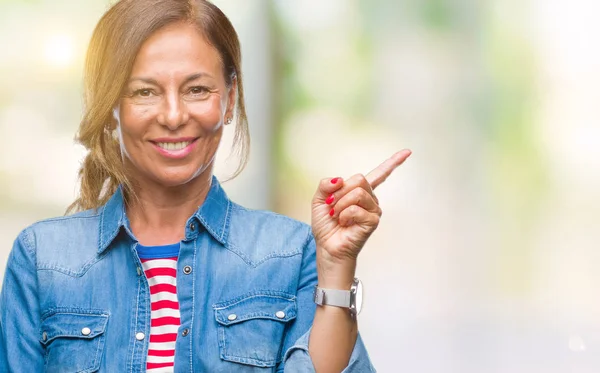 Kameraya bakarak yan el ve parmak ile işaret orta yaş İspanyol kadın kıdemli yüzünde kocaman bir gülümseme ile izole arka plan üzerinde.