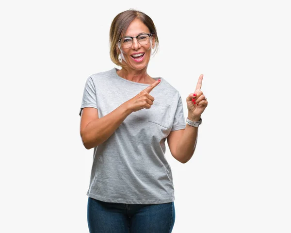 中年资深西班牙裔妇女戴眼镜在孤立的背景下微笑着 看着相机指着两只手和手指的侧面 — 图库照片