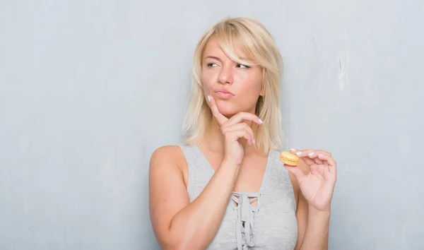 Vuxen Kaukasisk Kvinna Över Grunge Grå Vägg Äta Macaron Allvarligt — Stockfoto