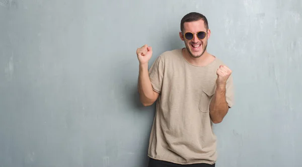 Joven Hombre Caucásico Sobre Pared Gris Grunge Usando Gafas Sol —  Fotos de Stock