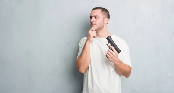 Young Caucasian Criminal Man Grey Grunge Wall Holding Gun Serious — Stock Photo, Image
