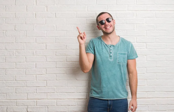 Joven Hombre Caucásico Pie Sobre Pared Ladrillo Blanco Con Gafas —  Fotos de Stock