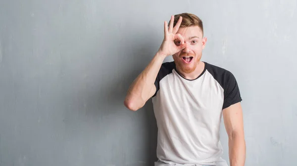 Giovane Uomo Rossa Oltre Muro Grunge Grigio Facendo Gesto Scioccato — Foto Stock