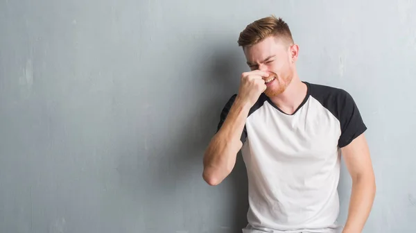 Unga Rödhårig Man Över Grå Grunge Vägg Lukta Något Illaluktande — Stockfoto