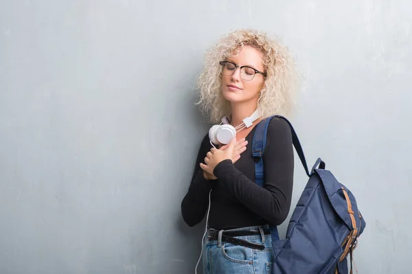 Mulher Loira Jovem Sobre Grunge Parede Cinza Usando Mochila Fones — Fotografia de Stock