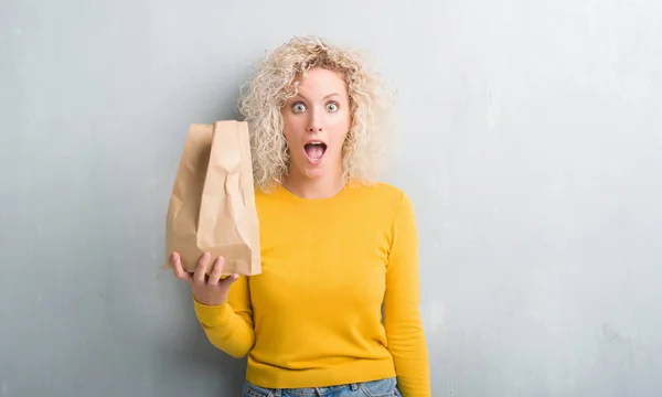 Joven Rubia Sobre Fondo Gris Grunge Sosteniendo Bolsa Papel Almuerzo —  Fotos de Stock