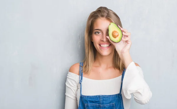 Hermosa Mujer Joven Sobre Pared Gris Grunge Comiendo Aguacate Con —  Fotos de Stock