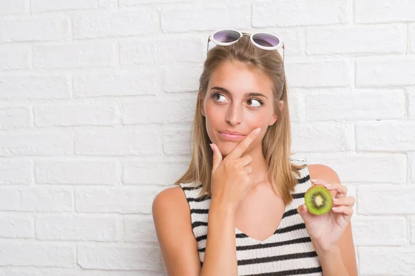 Schöne Junge Frau Über Weiße Backsteinmauer Essen Grüne Kiwi Ernstes — Stockfoto