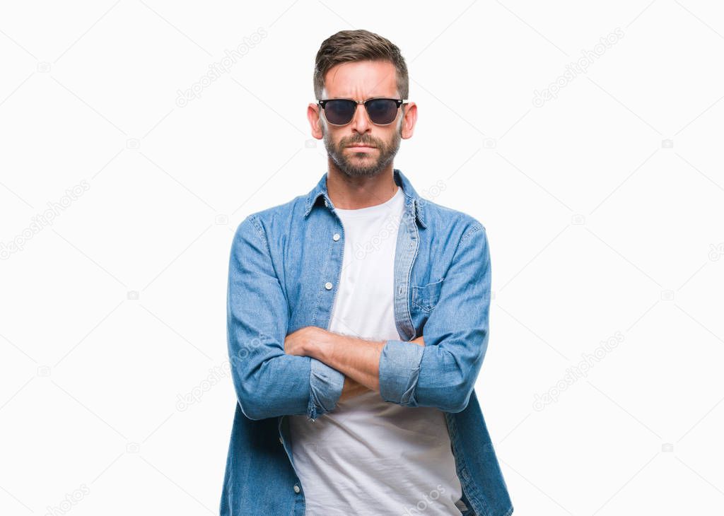 Young handsome man wearing sunglasses over isolated background skeptic and nervous, disapproving expression on face with crossed arms. Negative person.