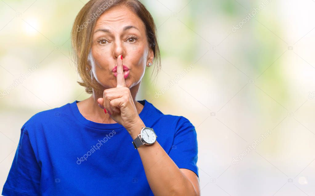 Middle age senior hispanic woman over isolated background asking to be quiet with finger on lips. Silence and secret concept.