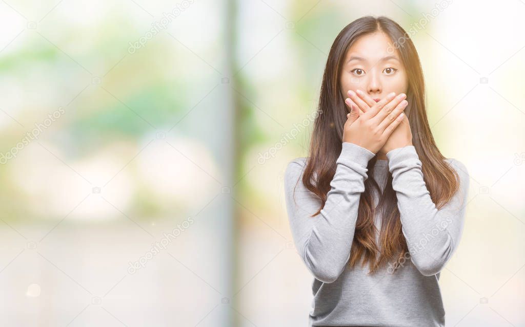 Young asian woman over isolated background shocked covering mouth with hands for mistake. Secret concept.