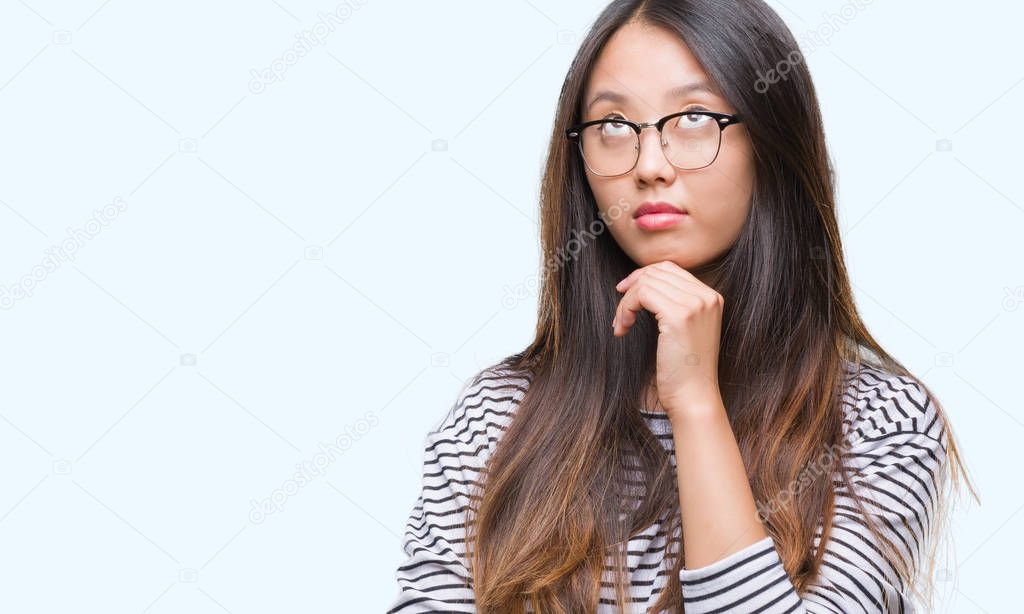 Young asian woman wearing glasses over isolated background with hand on chin thinking about question, pensive expression. Smiling with thoughtful face. Doubt concept.