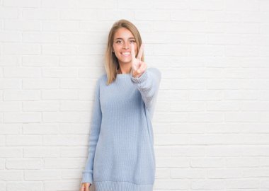 Beyaz tuğla duvar zafer işareti yapıyor parmak gösterilen kamera seyir gülümseyen güzel genç kadın. İki numaralı.